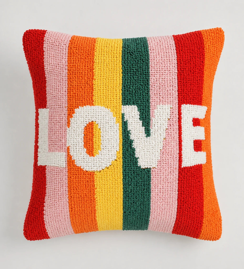 Colorful striped pillow with the word 'LOVE' on a light gray background